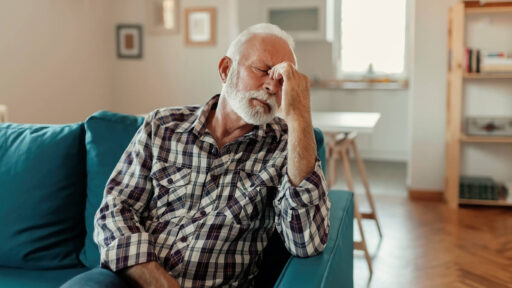 A man with his hand to his face and eyes closed, indicating fatigue. Sleep studies for sleep apnea are available at Astera Health in Wadena, MN.